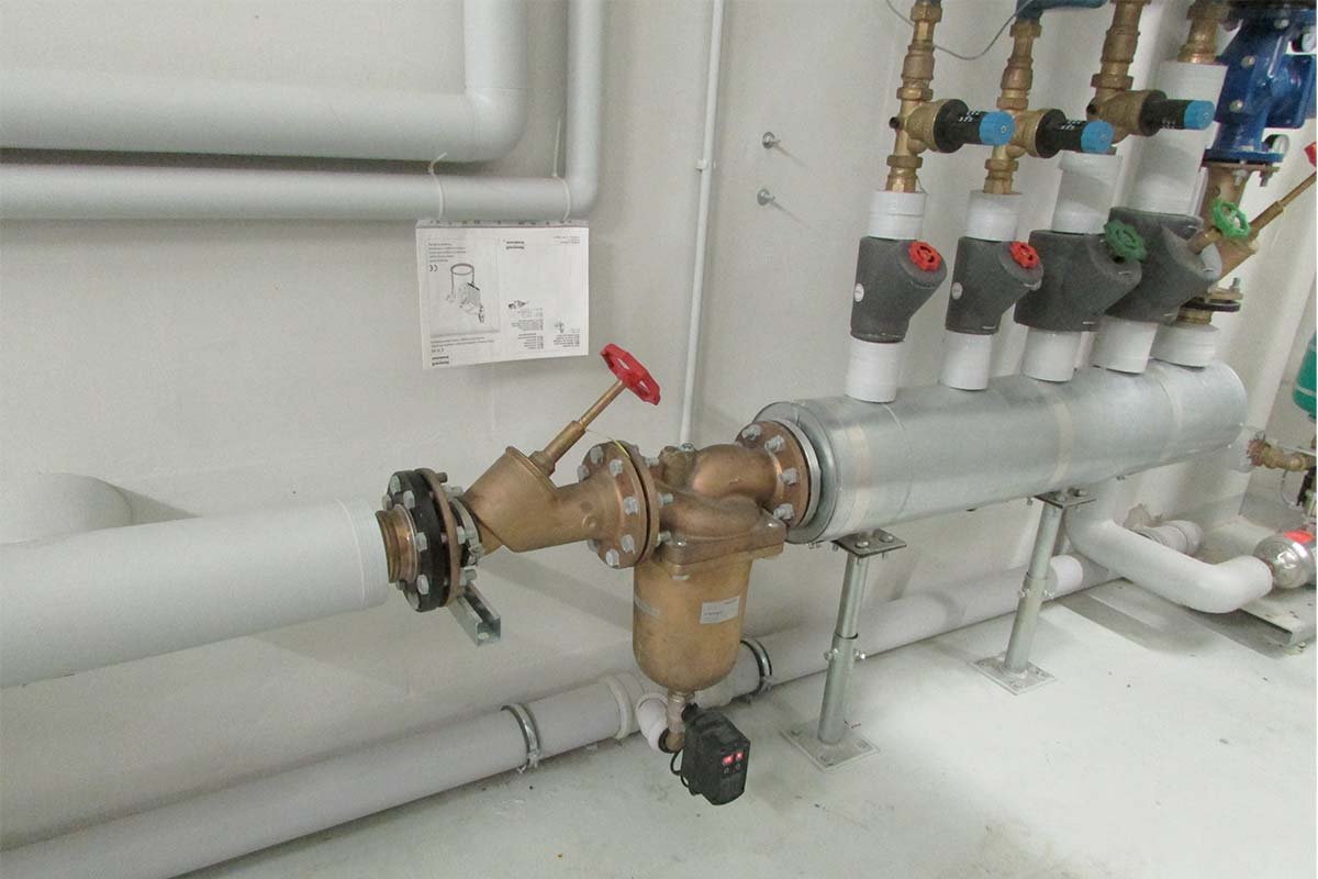 Ein detaillierter Blick auf eine Wasserinstallationsanlage mit einem Messgerät und verschiedenen Ventilen, die farblich gekennzeichnet sind.