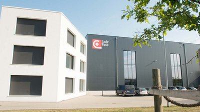 Im Vordergrund sind parkende Autos sichtbar, während im Hintergrund das Jade Pack Logo auf der grauen Wand leuchtet.