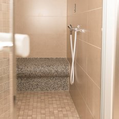 Ein einladender Duschbereich mit glatten, hellen Fliesen und einer komfortablen Sitzgelegenheit aus Mosaik.