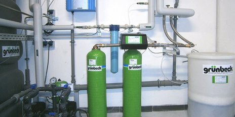Das Bild zeigt eine technische Installation mit Wasserfiltern, Rohren und einem großen Behälter zur Wasseraufbereitung.