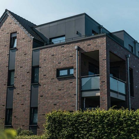 Die Architektur des Hauses kombiniert traditionelle und moderne Elemente, mit einem Balkon und einem klaren Himmel im Hintergrund.