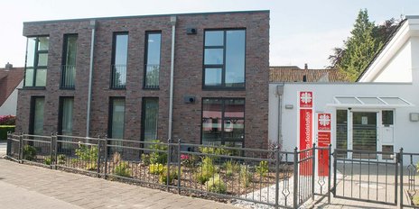 Die Fassade eines zweigeschossigen Hauses mit Backsteinoptik und einem einladenden Eingangsbereich der Caritas-Sozialstation.