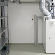 Der Raum zeigt eine saubere, moderne Heizungsanlage, umgeben von leeren Regalen, die auf eine praktische Nutzung hinweisen.