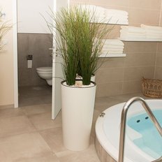 Ein modernes Badezimmer mit einem entspannenden Whirlpool, dekorativen Pflanzen und einem Regal voller frischer Handtücher.