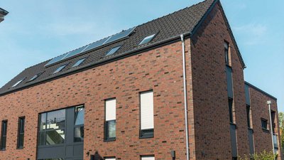 Ein modernes, zweigeschossiges Gebäude mit einer Fassade aus roten Ziegeln und großen Fenstern, die viel Licht hereinlassen.