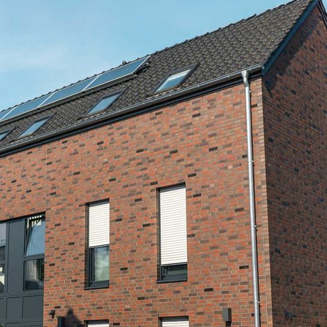 Ein modernes, zweigeschossiges Gebäude mit einer Fassade aus roten Ziegeln und großen Fenstern, die viel Licht hereinlassen.
