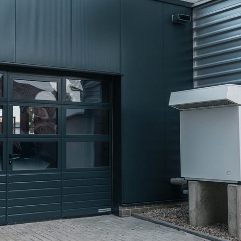 Eine moderne Garage mit einem großen Fenster und einer Ladestation für Elektrofahrzeuge an der Wand.