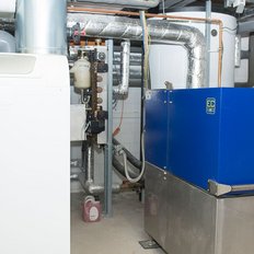 Eine technische Einrichtung im Heizungsraum mit einer weißen Heizungsanlage und einem blauen Gerät, das für die Wärmeversorgung sorgt.