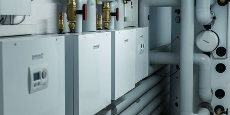 Die Installation zeigt Heizgeräte und Rohre in einem technischen Raum, alles in einem sauberen, weißen Design.