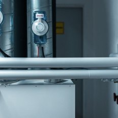 Die Rohre mit Druckmessgeräten sind Teil einer technischen Installation in einem Raum mit neutralen Wänden und minimalistischem Design.