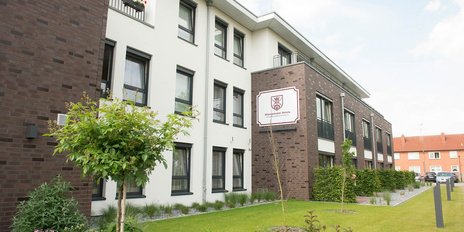 Das Gebäude zeigt eine Kombination aus hellen und dunklen Materialien, mit einem Schild, das den Namen 'Wohnpark Apen' trägt.